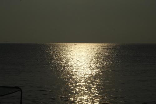 a large body of water with the sun reflecting on it at Clara's Beach Inn in Trincomalee