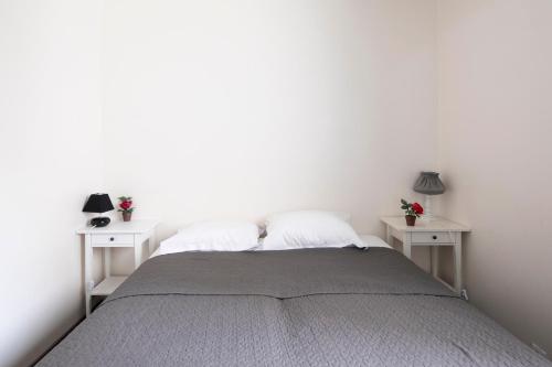 - une chambre avec des murs blancs et un lit avec 2 tables dans l'établissement Emile Zola Asnière - KP -Spacious apt for 6 with porch Asnière sur Seine, à Asnières-sur-Seine