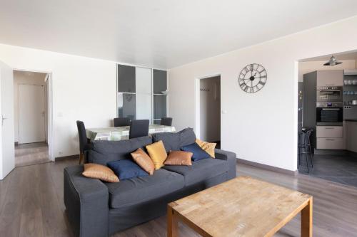 un salon avec un canapé gris et une table dans l'établissement Emile Zola Asnière - KP -Spacious apt for 6 with porch Asnière sur Seine, à Asnières-sur-Seine