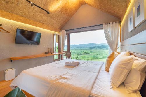 a bedroom with a large bed with a large window at Villa Sare - House with panorama rice field view in Yogyakarta