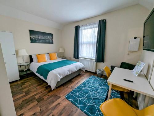 Un dormitorio con una cama, un escritorio y una mesa. en King En suite Room Near Heathrow Airport, en Hounslow