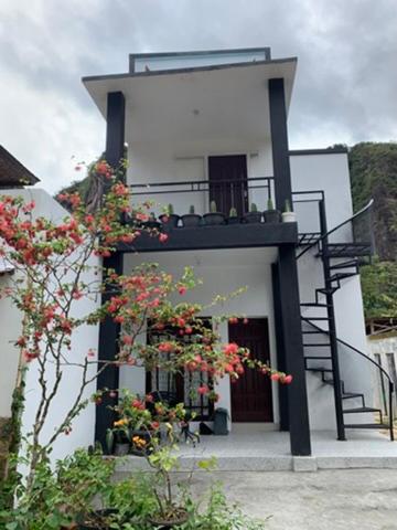 a white building with a staircase and flowers on it at Zico Homestay in Andalas