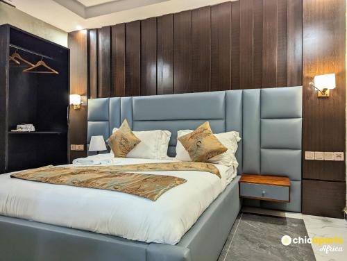 a bedroom with a large bed with a blue headboard at Chic apart with parking near the airport in Douala