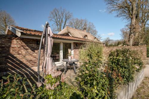 a patio with a table and an umbrella in front of a house at Rustig Tiny House in het groen nabij Enschede & UT in Enschede