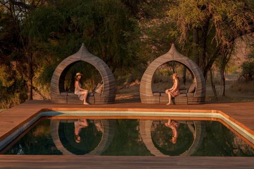 a painting of two people sitting in arches by a pool at Sashwa River of Stars Plant-Based Wellness Safari Lodge in Hoedspruit