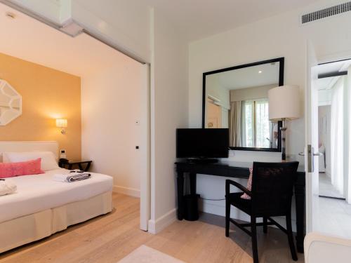 a bedroom with a bed and a desk and a mirror at California Park Hotel in Forte dei Marmi