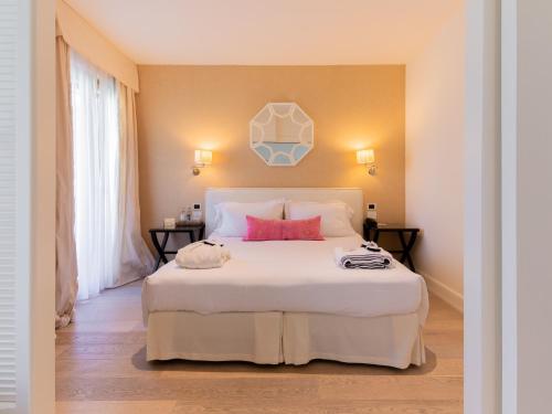 a bedroom with a large white bed with pink pillows at California Park Hotel in Forte dei Marmi