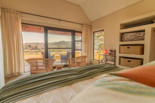 a bedroom with a bed and a large window at Sashwa River of Stars Plant-Based Wellness Safari Lodge in Hoedspruit