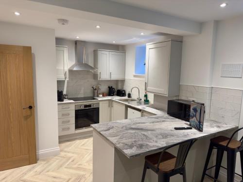 une cuisine avec des armoires blanches et un comptoir en marbre dans l'établissement Fletcher - A Converted Church Luxe Apartment, à Gillingham