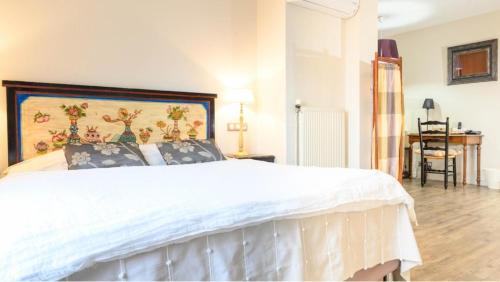 a bedroom with a white bed with a painting on the wall at Logis hotel-restaurant les collines 59 route des crêtes in Cublac