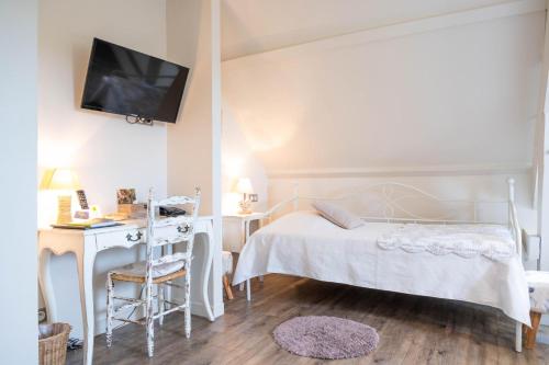 a bedroom with a bed and a desk and a tv at Logis hotel-restaurant les collines 59 route des crêtes in Cublac