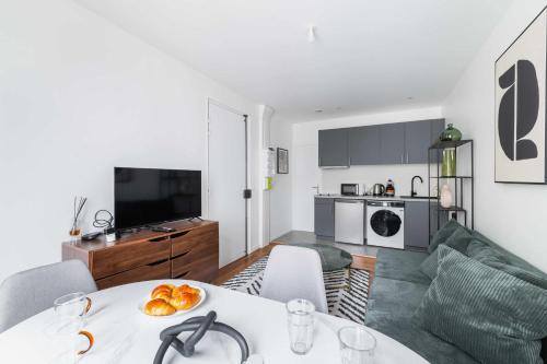 un salon avec une table et une cuisine dans l'établissement Cosy 2 Pieces au Coeur du 19e - 4P, à Paris
