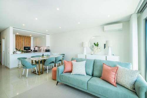 a living room with a blue couch and a kitchen at Sob O Mar III in Armação de Pêra