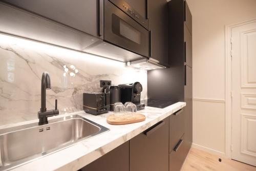 une cuisine avec un évier et un micro-ondes dans l'établissement Appartement luxe 2 chambres Grands Boulevards 4-6P, à Paris