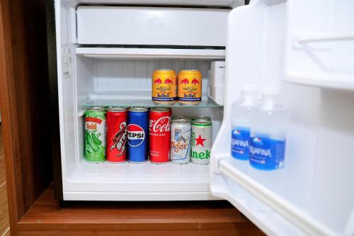 an open refrigerator filled with cans of soda at Suka Hotel in Tây Ninh
