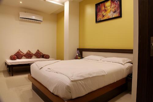a bedroom with a bed and a bench in it at Hotel Shubhashree Comfort in Bijāpur