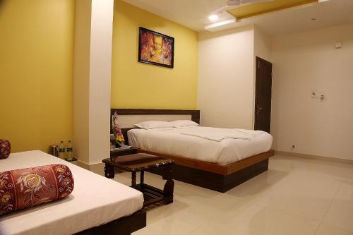 a bedroom with two beds and a picture on the wall at Hotel Shubhashree Comfort in Bijāpur