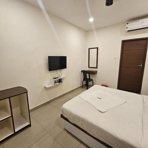 a bedroom with a bed and a tv on the wall at Heres Haut Residency in Ernakulam