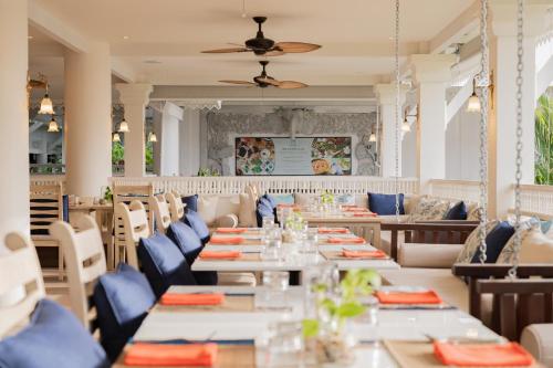 a dining room with tables and blue chairs at Thavorn Palm Beach Resort Phuket in Karon Beach