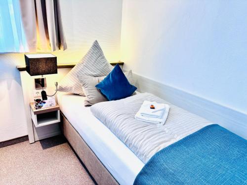 a bed with blue pillows and a book on it at Inselsünn Hotel und Apartments in Spiekeroog