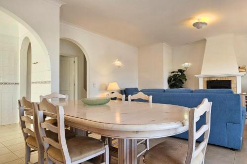 a dining room with a table and a blue couch at Quinta da Floresta – Santo António Villas, Golf & Spa in Budens