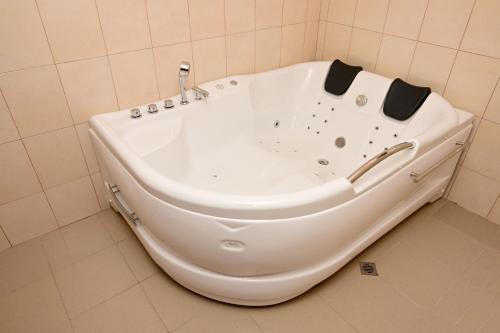 a white bath tub in a tiled bathroom at Ловна резиденция ДЛС Извора in Devin