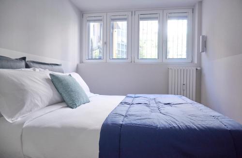 a white bedroom with a bed and two windows at Milan Retreats Fiera Milano City in Milan