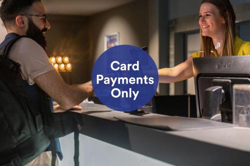 a man and woman standing at a counter with the words card payments only at a&o Köln Neumarkt in Cologne