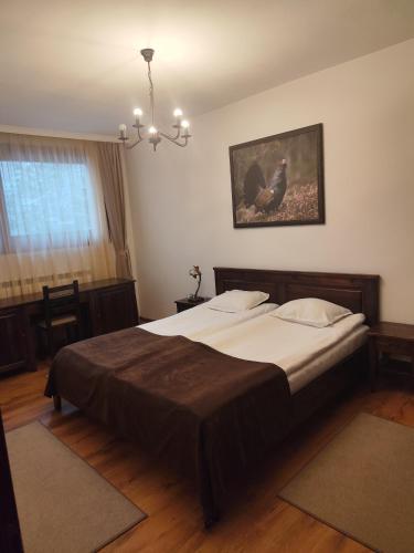 a bedroom with a large bed with a chandelier at Ловна резиденция ДЛС Извора in Devin