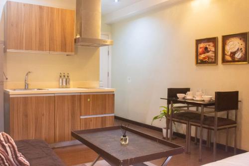 a living room with a table and a kitchen at The Gramercy Residences in Manila