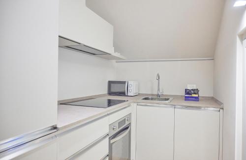 a white kitchen with a sink and a microwave at Milan Retreats Fiera Milano City in Milan