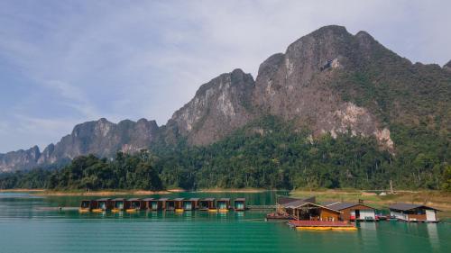 a group of houses on the water in front of a mountain at 360 issara Floating Resort in Ban Bang Kaeo