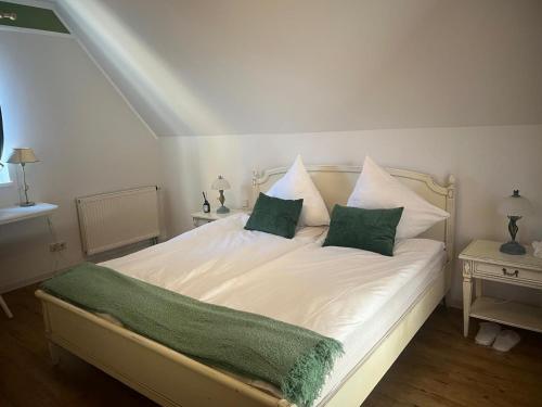 a white bed with two green pillows on it at Landgasthaus Zum Engel in Neuleiningen