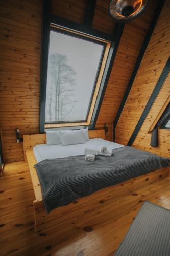 a bed in a wooden room with a large window at Ordu Bungalov-Loin du Monde in Perşembe