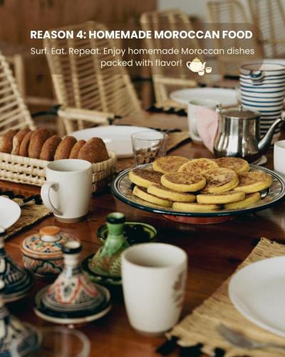 a table with a plate of cookies and coffee cups at Monza Surf House in Tamraght Ouzdar
