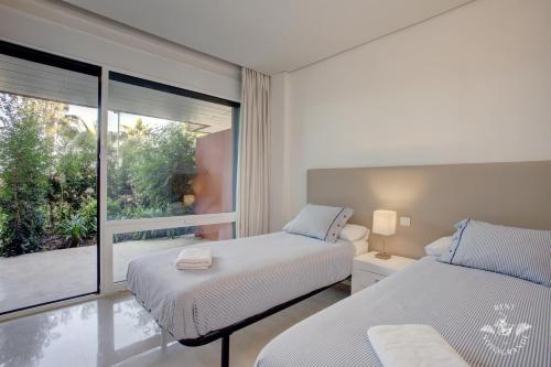 a bedroom with two beds and a large window at Ribera del Marlin - Sotogrande in Sotogrande