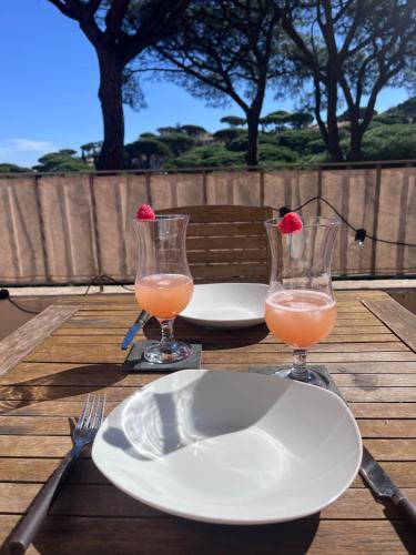 une table avec deux assiettes et deux verres de jus dans l'établissement Résidence la Pinède, à Sainte-Maxime