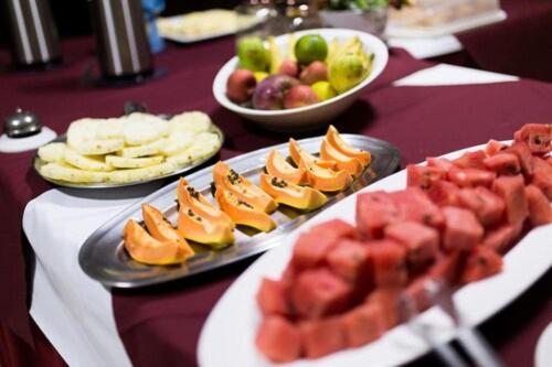 a table topped with plates of fruit and snacks at OYO Hotel La Dolce Vita, Rio das Ostras in Rio das Ostras