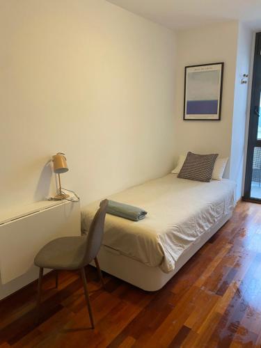 a small bedroom with a bed and a chair at Mai&Maud Fira Apartment in Hospitalet de Llobregat