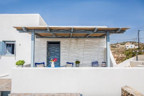 a balcony with blue chairs and a pergola at Althea Studios in Donoussa