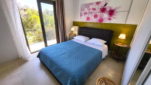 Un dormitorio con una cama azul y una ventana. en Complex HARMONY with infinity pool, en Kalívia Thorikoú