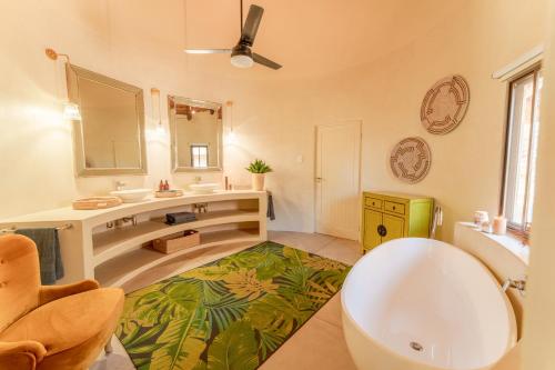 a bathroom with a tub and a sink and a mirror at Sashwa River of Stars Plant-Based Wellness Safari Lodge in Hoedspruit