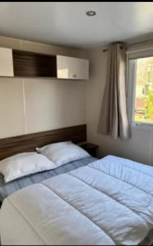 une chambre avec un grand lit avec une fenêtre dans l'établissement Mobil home 557, à Gastes