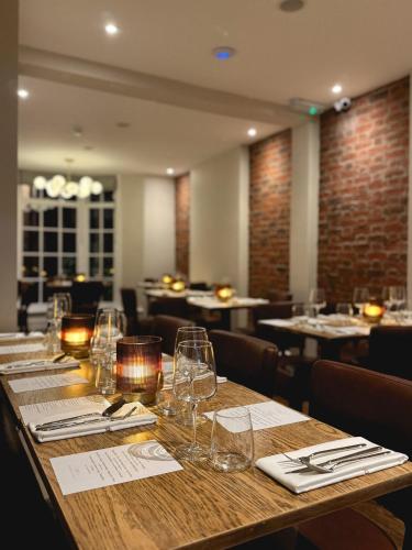 a long wooden table in a restaurant with wine glasses at Orla Restaurant & Rooms in Lindfield