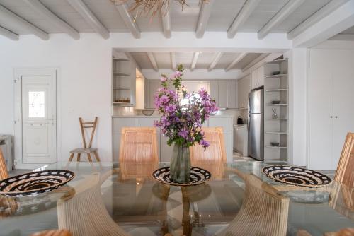 a dining room with a glass table with a vase of flowers at Cavos Paros Private Pool Oasis in Aliki