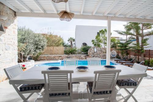 a patio with a table and chairs and a swimming pool at Cavos Paros Private Pool Oasis in Aliki