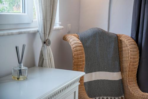 a wicker chair with a white table and a window at Cavos Paros Private Pool Oasis in Aliki