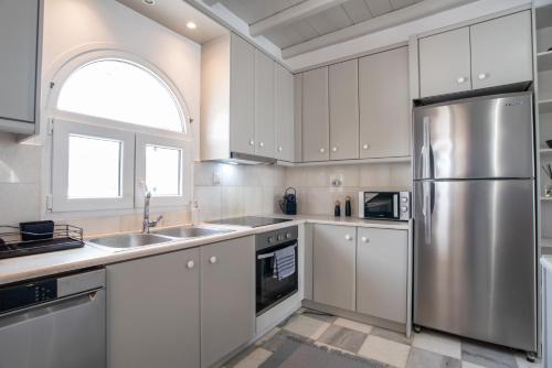 a kitchen with white cabinets and a stainless steel refrigerator at Cavos Paros Private Pool Oasis in Aliki