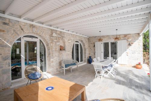 a patio with a table and chairs and a stone wall at Cavos Paros Private Pool Oasis in Aliki