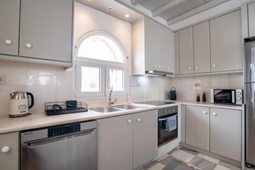a kitchen with white cabinets and a sink at Cavos Paros Private Pool Oasis in Aliki